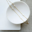 Gold necklace with pearls on a white dish