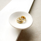 Textured solid gold hoops in a white dish