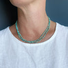 Woman wearing white tank and a long knotted turquoise necklace on a navy background