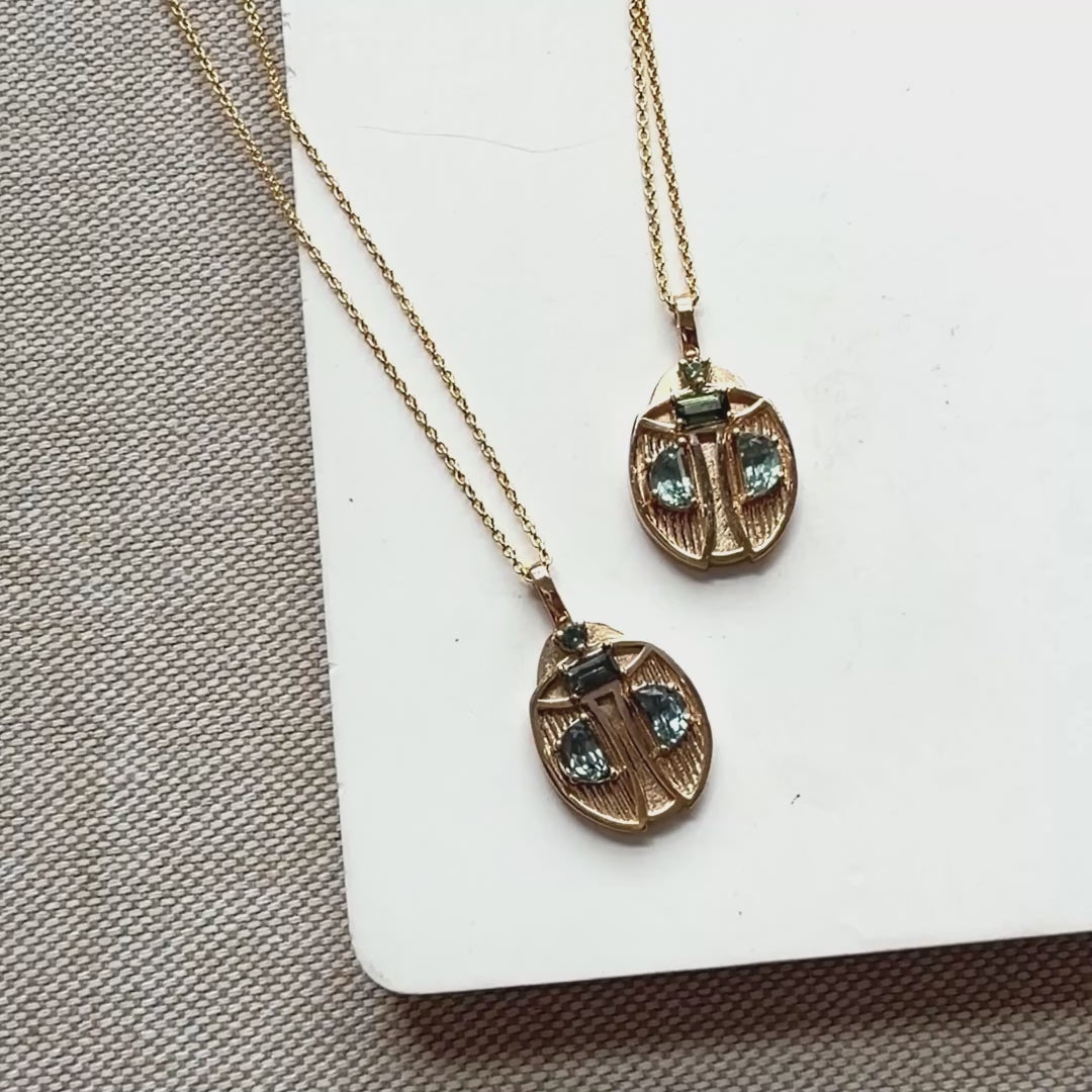 Two gold beetle pendants set with Montana sapphires