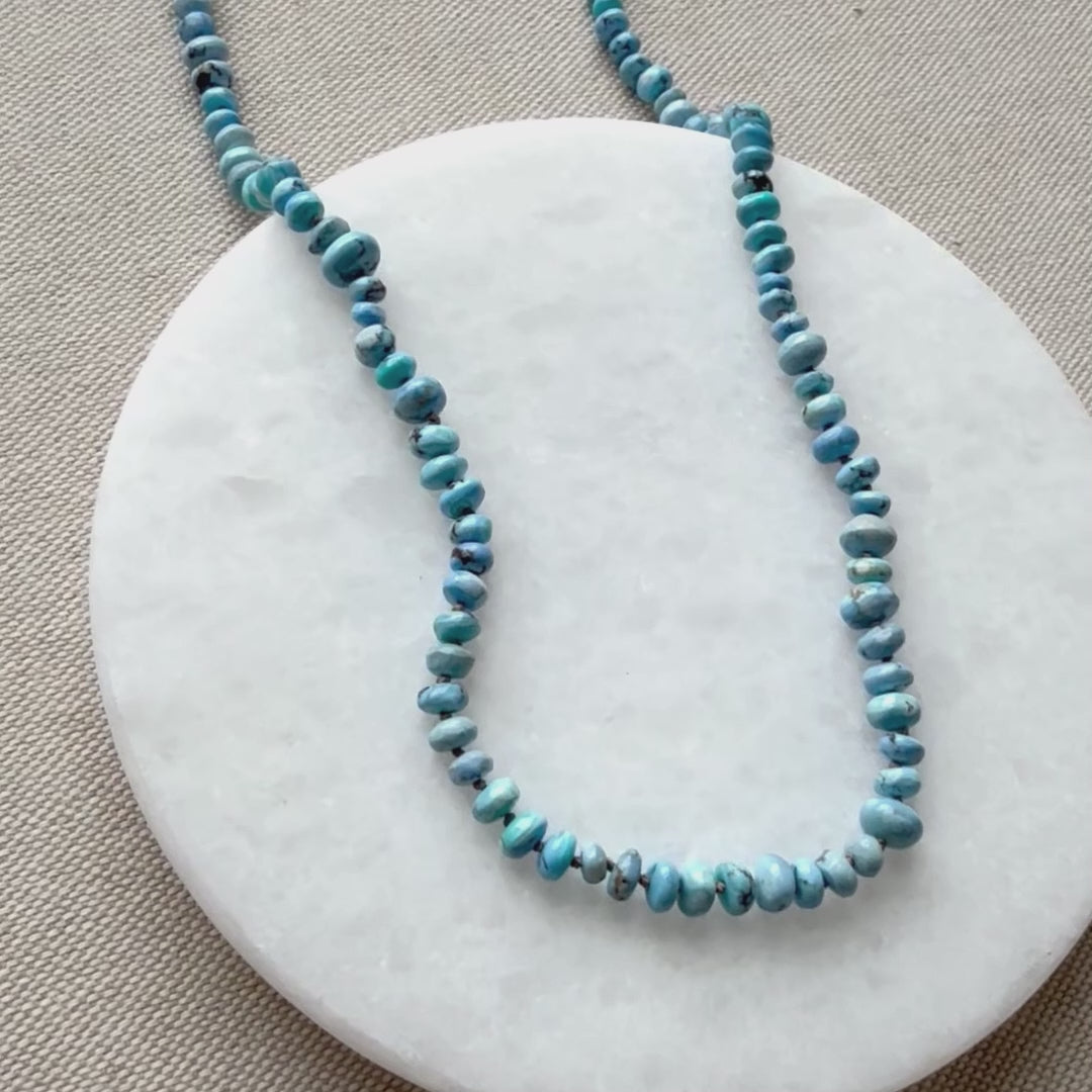Close up of Golden Hill turquoise knotted necklace on a white round dish.