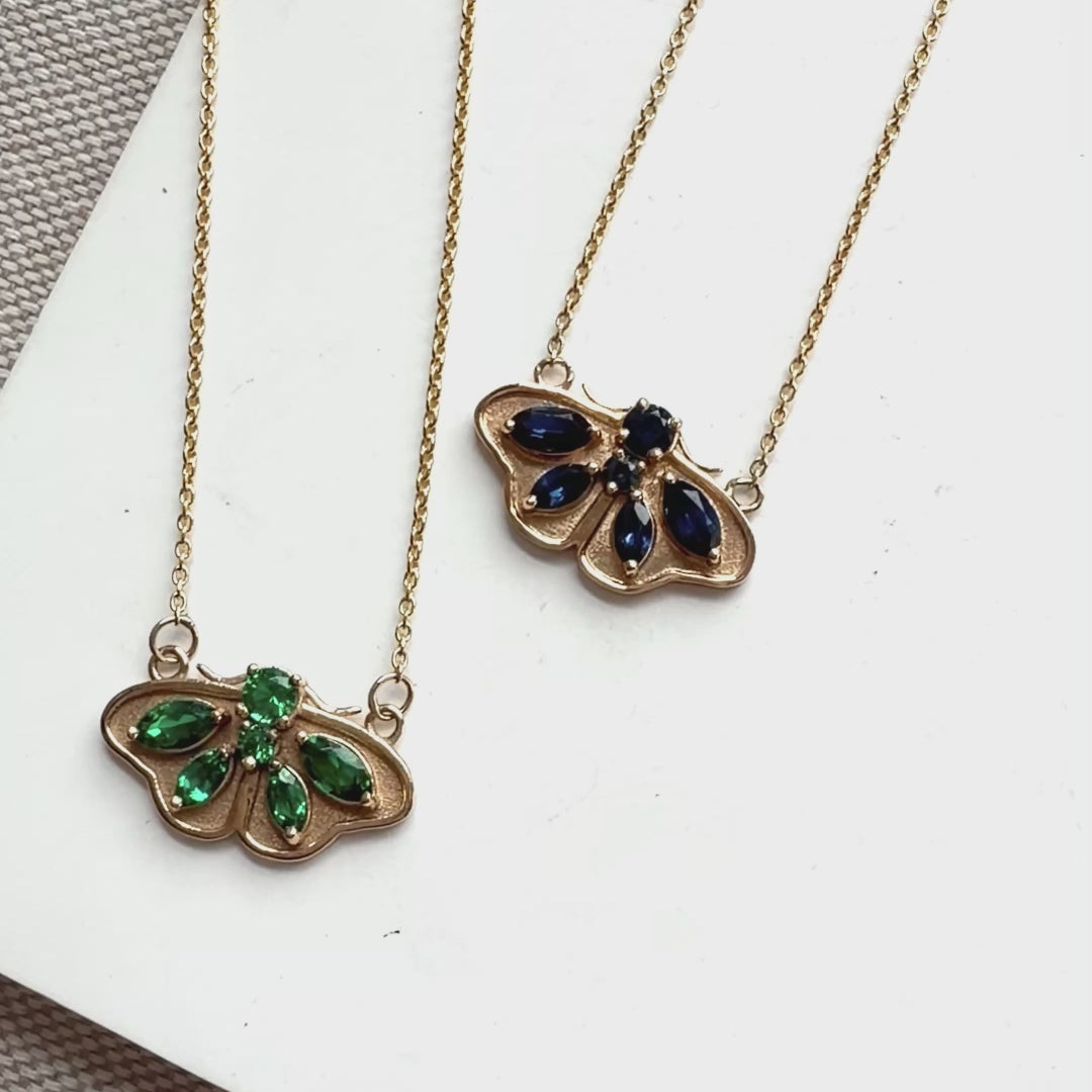 Two 14k gold butterfly necklaces, one set with emeralds and one set with blue sapphires