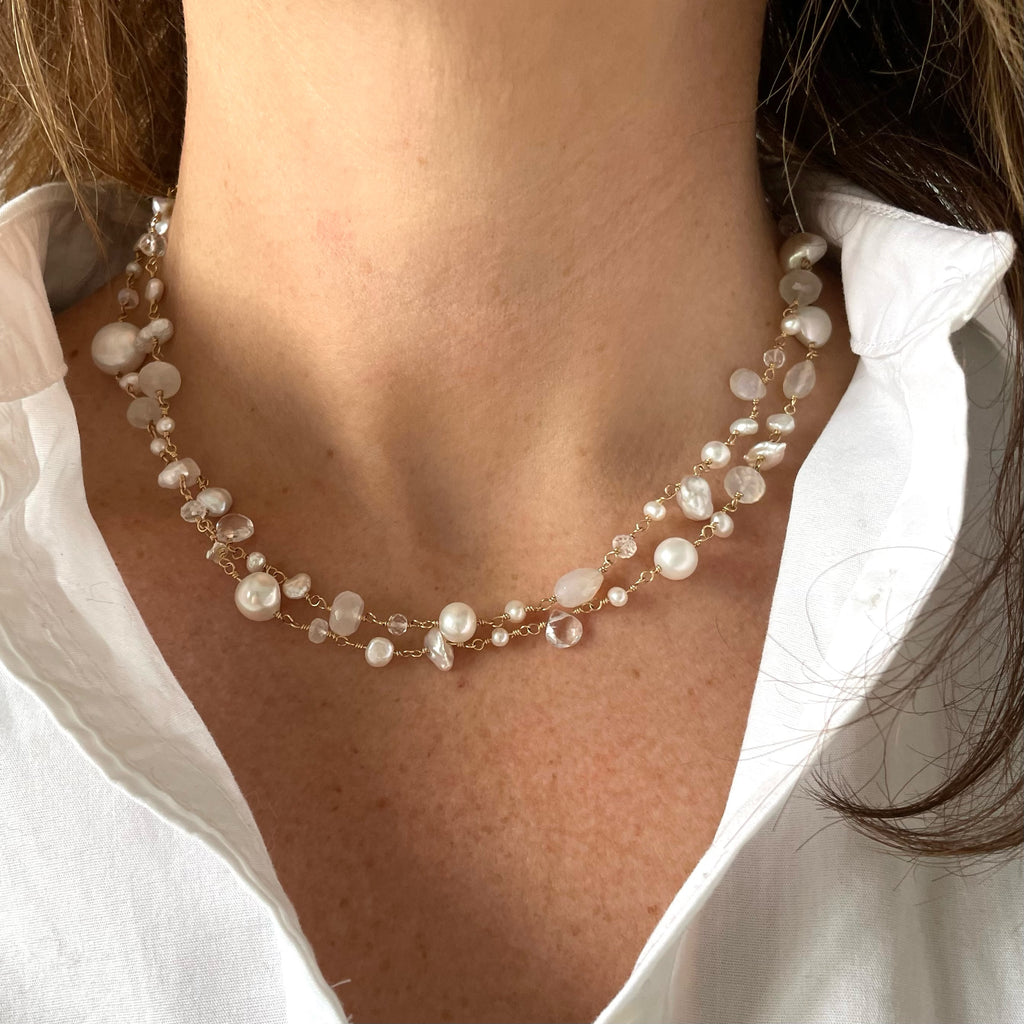 Woman's neckline wearing white button down shirt with a doubled gold, pearl and gemstone long statement pearl necklace with wire wrapped moonstone, white chalcedony, white topaz, and freshwater pearls. Poppy Linen necklace by Sarah Cornwell Jewelry
