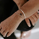 Close up of woman's wrist with silver textured bangle bracelet with the words "always with you" stamped on the inside and 2 silver gemstone bracelets . Always with You Bangle by Sarah Cornwell Jewelry