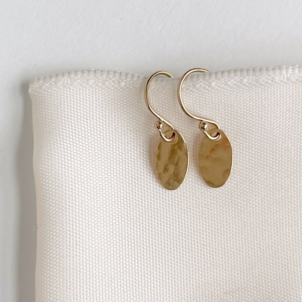 Gold Brooklyn Earrings by Sarah Cornwell Jewelry.  Dainty textured gold oval earrings with a .5 in drop on a white background.