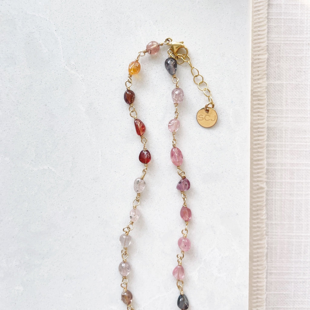 17 inch gold and gemstone necklace with a full strand of wire wrapped gradient colored red, purple and pink spinel gemstones. Cain Necklace by Sarah Cornwell Jewelry