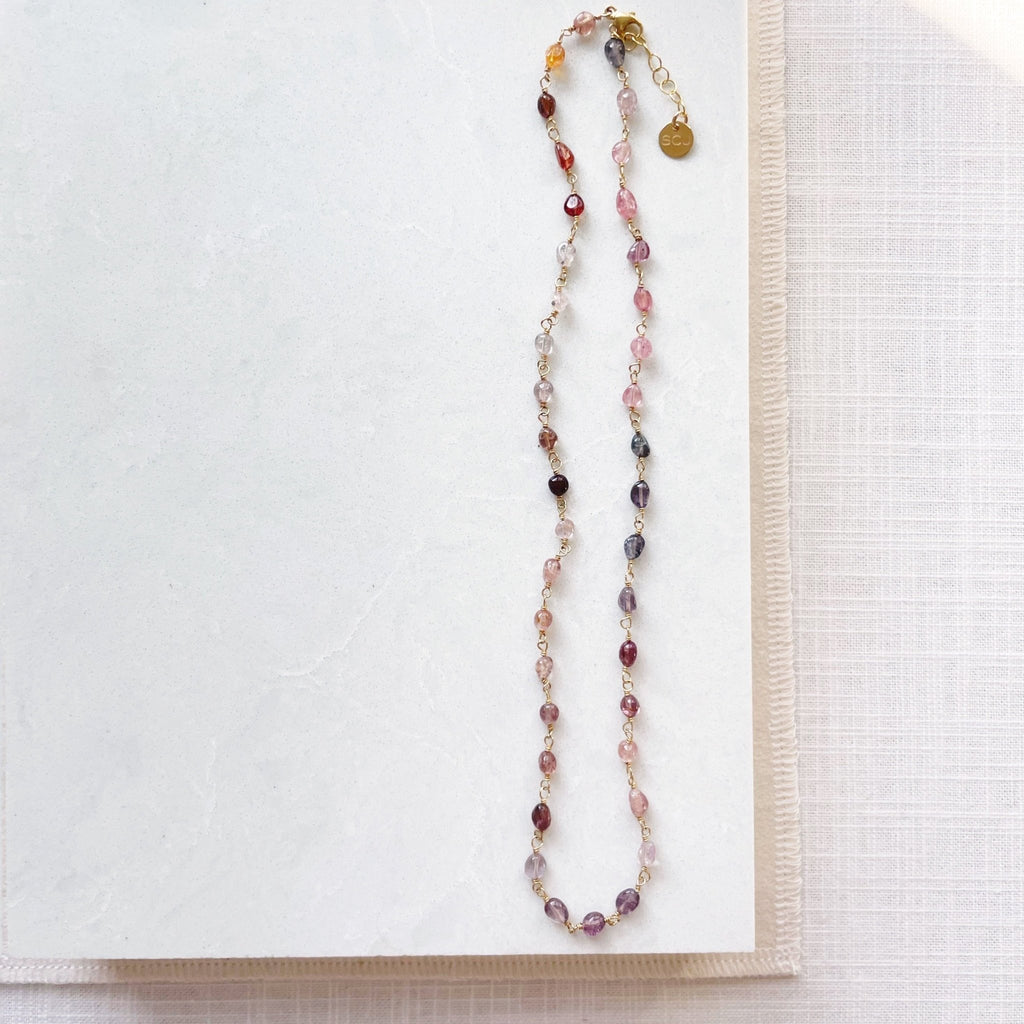 17 inch gold and gemstone necklace with a full strand of wire wrapped gradient colored red, purple and pink spinel gemstones. Cain Necklace by Sarah Cornwell Jewelry