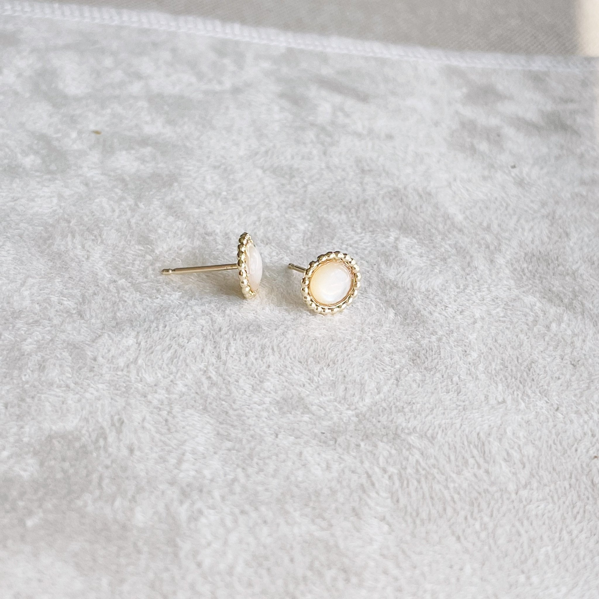 Pair of 6mm gold and mother of pearl stud earrings with a beaded bezel setting. Chantilly Studs by Sarah Cornwell Jewelry