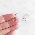 Close up of gold and silver simple circle stud earrings. Hand holding one earring.Circle Studs by Sarah Cornwell Jewelry