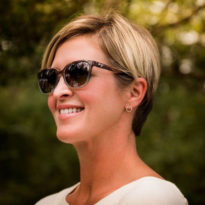 Side view of woman with short blonde hair wearing sunglasses and a white shirt with gold simple circle stud earrings. Circle Studs by Sarah Cornwell Jewelry