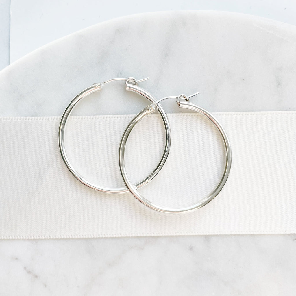 Silver Grande Hoop Earrings by Sarah Cornwell Jewelry. Large simple, everyday silver hoop earrings on a white background.