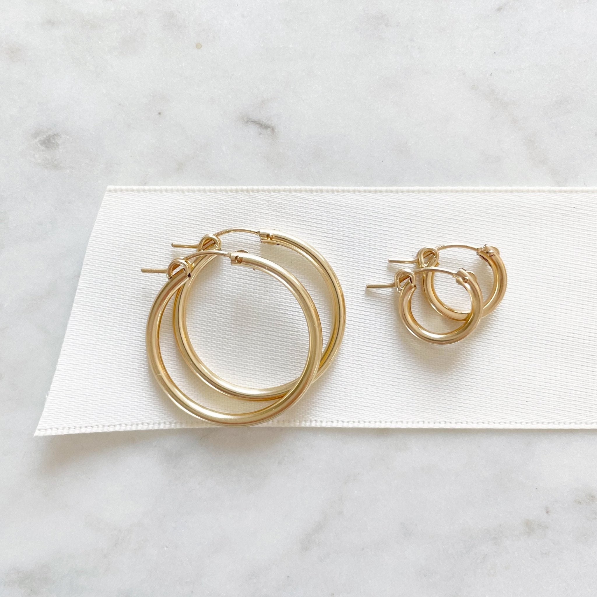 Gold Demi and Grande Hoops by Sarah Cornwell Jewelry.  Large and small simple, everyday gold hoop earrings on a white background.