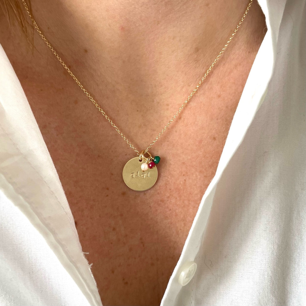 Woman's neckline wearing white button down with gold gigi disc and wire wrapped gemstone necklace with 3 white, red and green gemstones. Gigi Necklace by Sarah Cornwell Jewelry