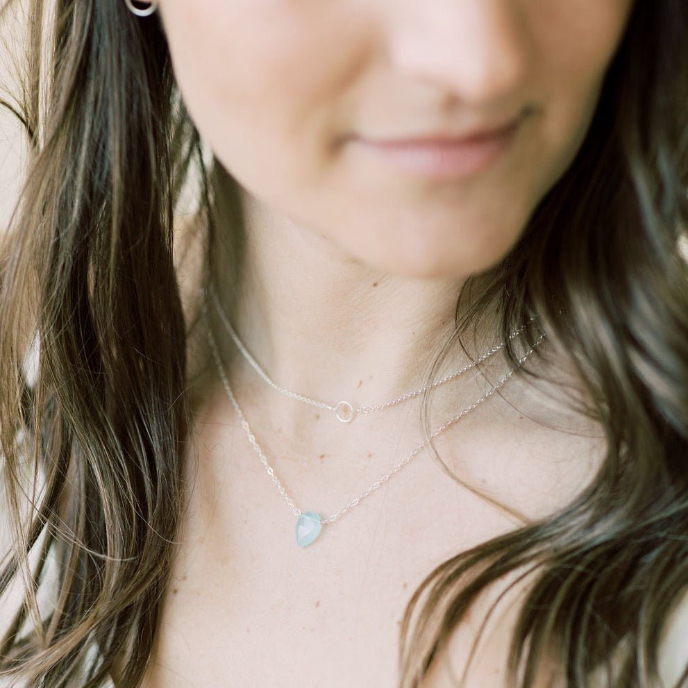 Woman's neckline wearing  17 inch silver pendant necklace with teardrop shaped aqua chalcedony pendant and silver gemstone layering necklace. Hampton Necklace by Sarah Cornwell Jewelry