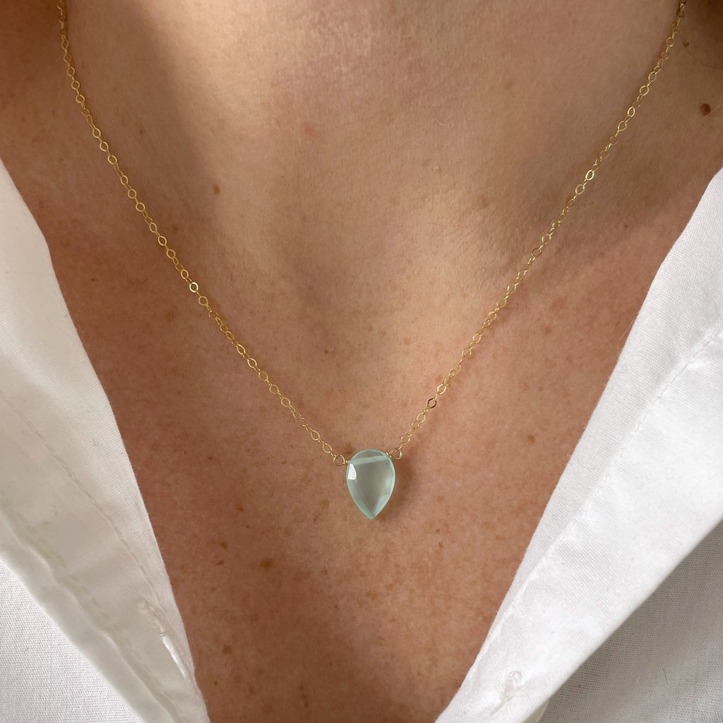 Woman's neckline wearing white shirt with 17 inch gold pendant necklace with teardrop shaped aqua chalcedony pendant. Hampton Necklace by Sarah Cornwell Jewelry