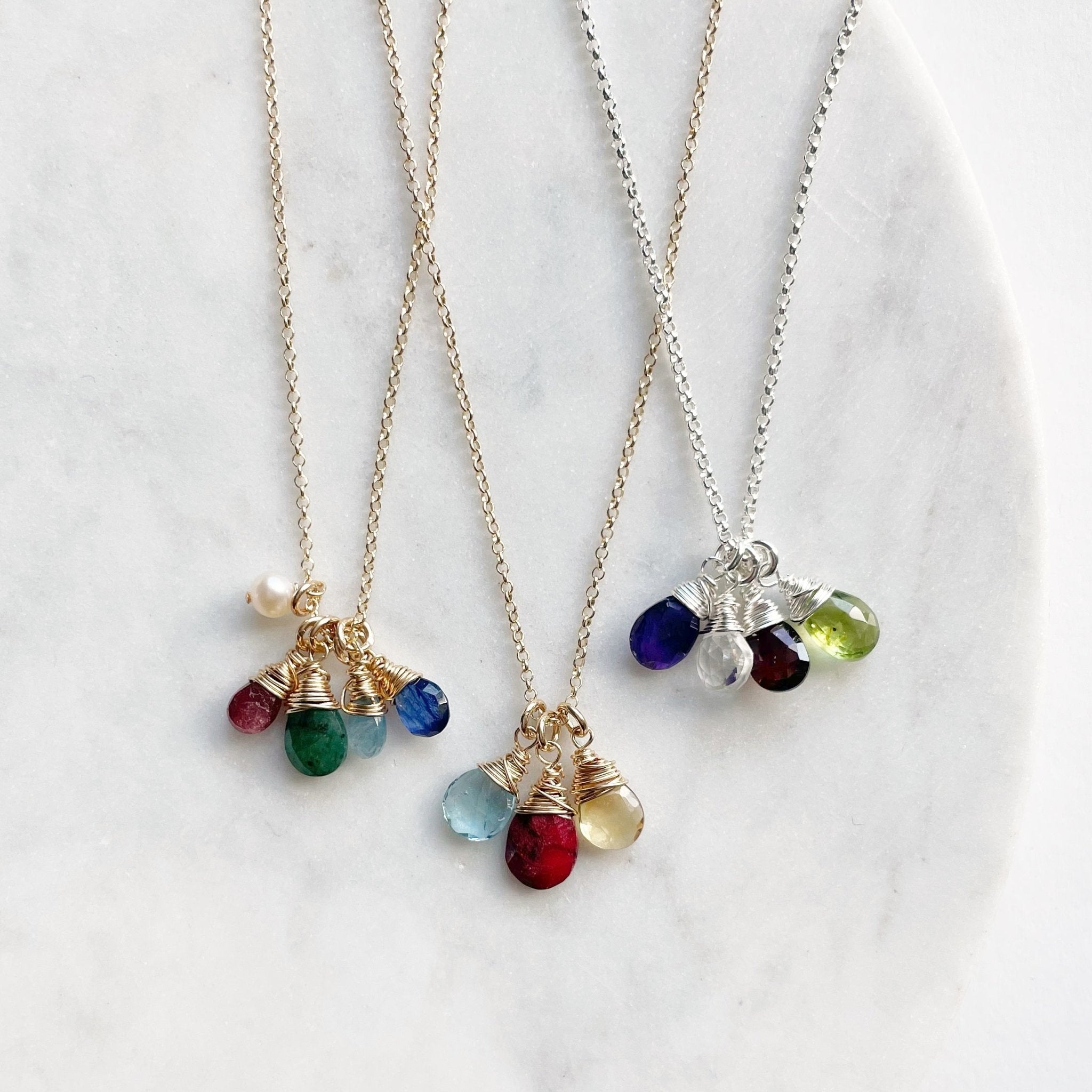 3 wire wrapped gemstone birthstone necklaces, 2 gold and one silver, with various numbers and types of gemstone pendants. Heritage Necklace by Sarah Cornwell Jewelry