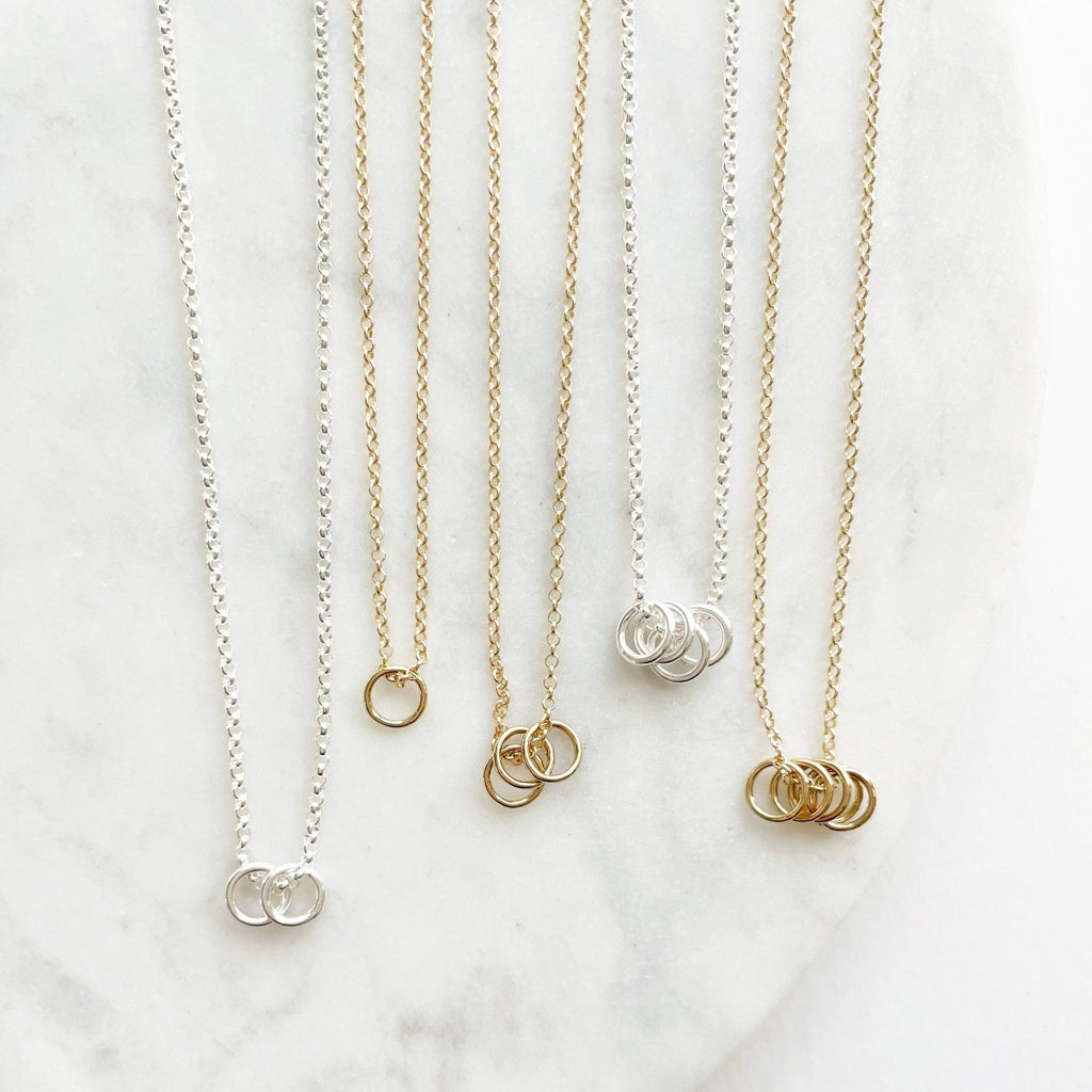 5 gold and silver necklaces with 1, 2, 3, 4 and 5 tiny gold and silver rings. Honor Necklace by Sarah Cornwell Jewelry