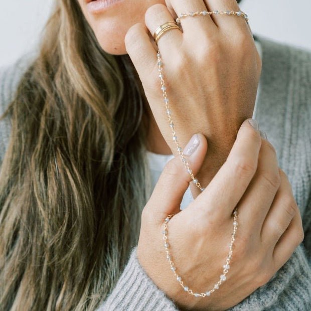 Woman's hands with gold rings holding a 17 inch gold and gemstone necklace with labradorite, zircon, and smokey topaz gemstones. Jonas Necklace by Sarah Cornwell Jewelry