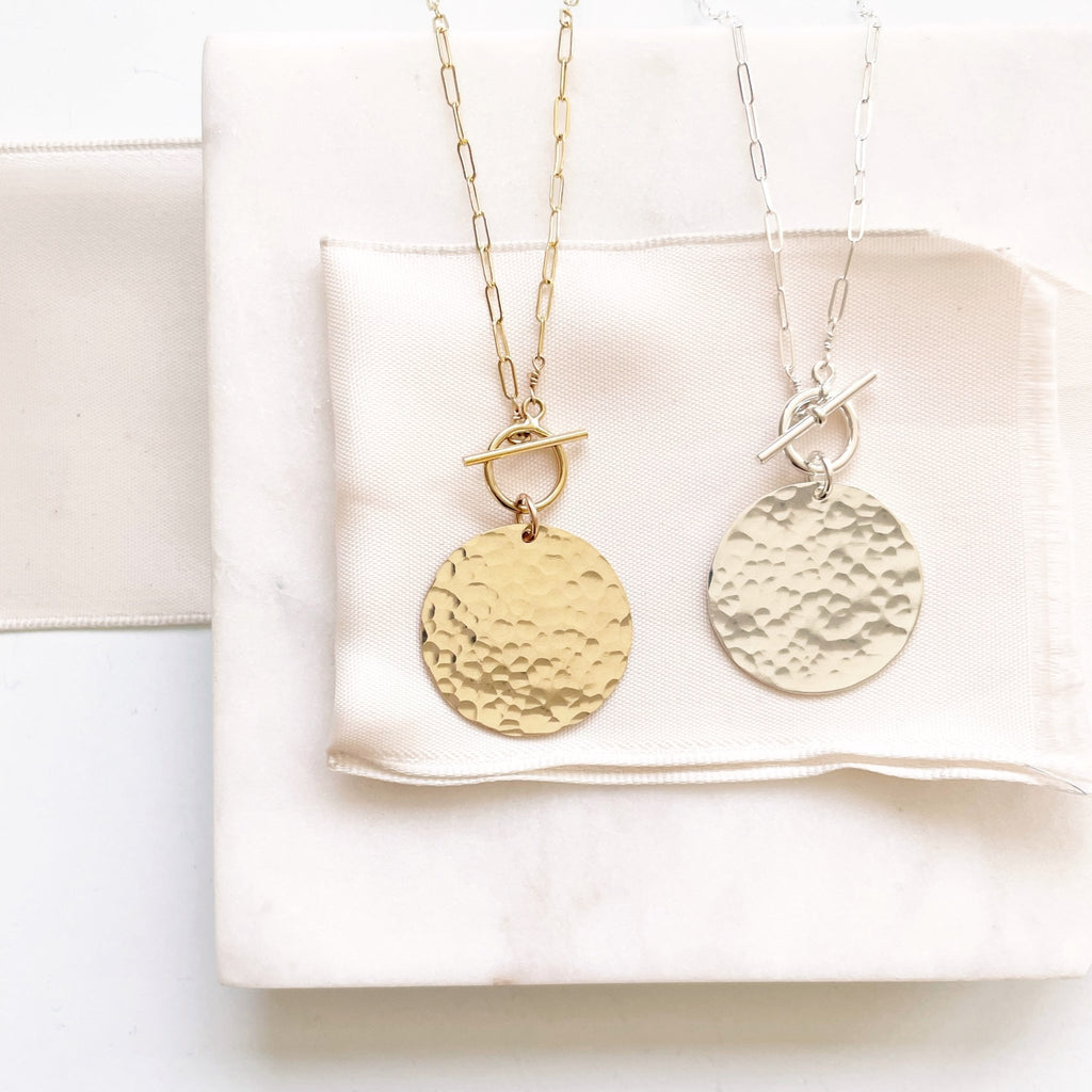 Gold and a silver statement necklaces with large textured discs and front toggles. Josephine Necklace by Sarah Cornwell Jewelry