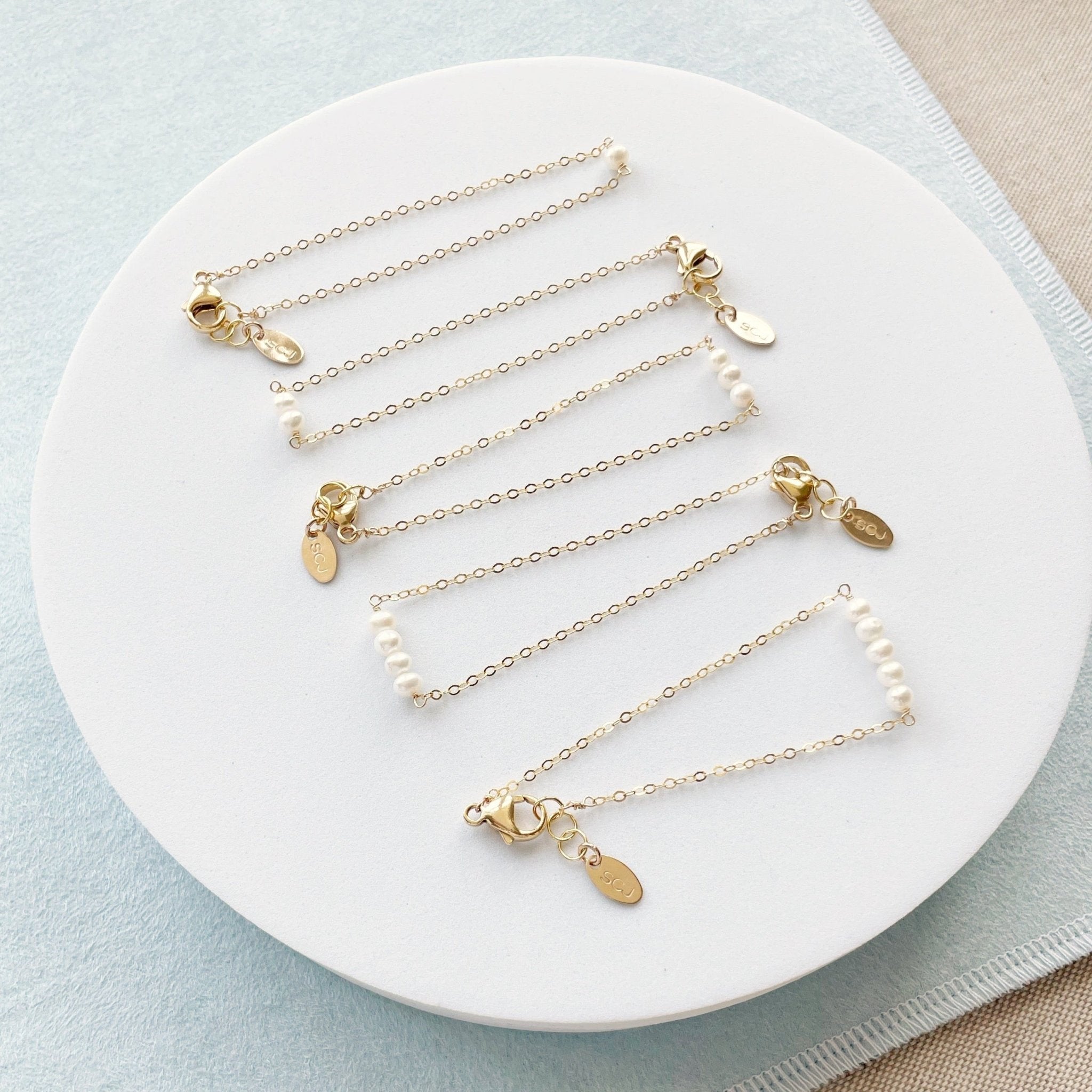 5 gold and pearl bracelets with various numbers of pearls close together. La Mere Bracelet by Sarah Cornwell Jewelry