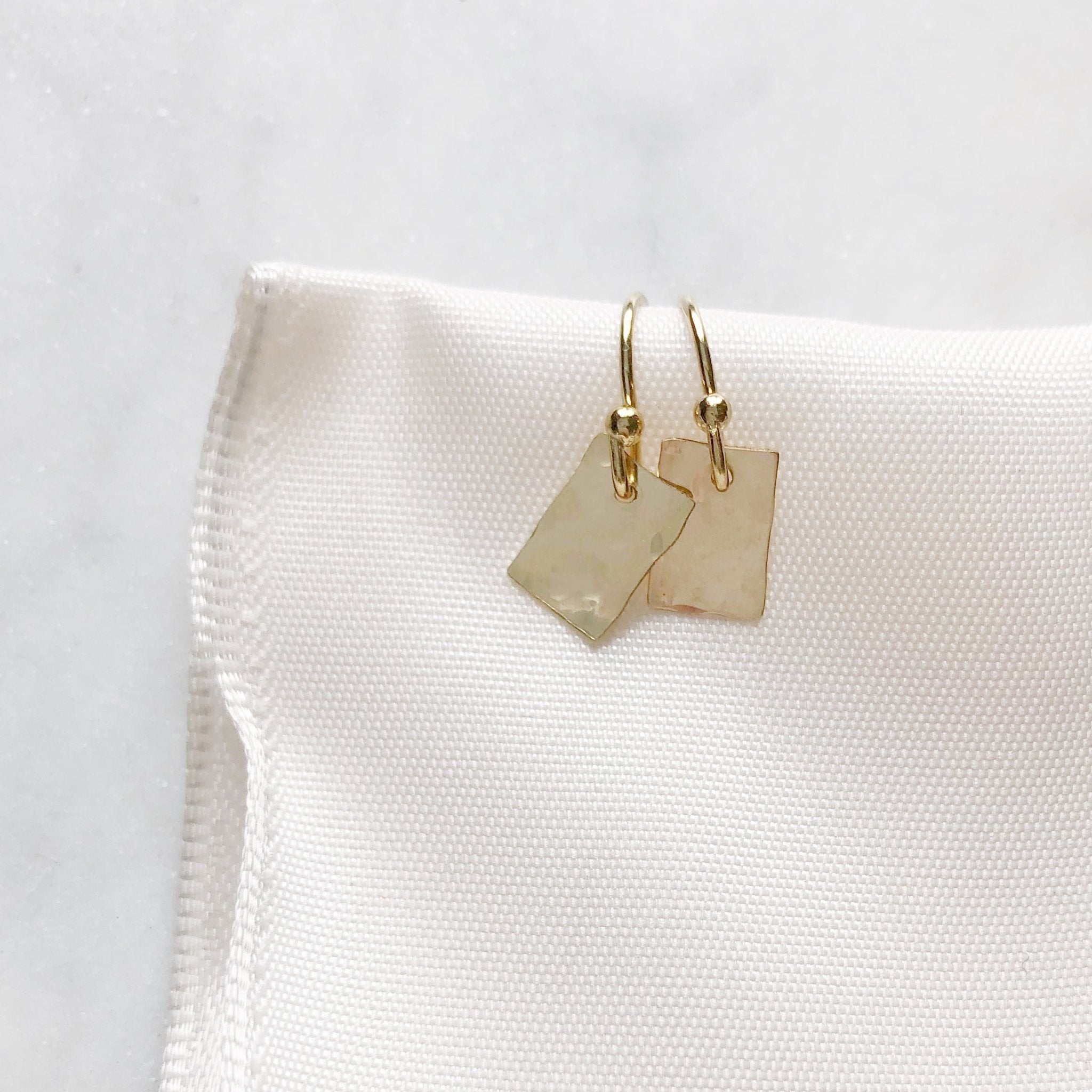 Gold Lordes Earrings by Sarah Cornwell Jewelry. Dainty, shimmery, gold textured rectangle earrings on a white background.