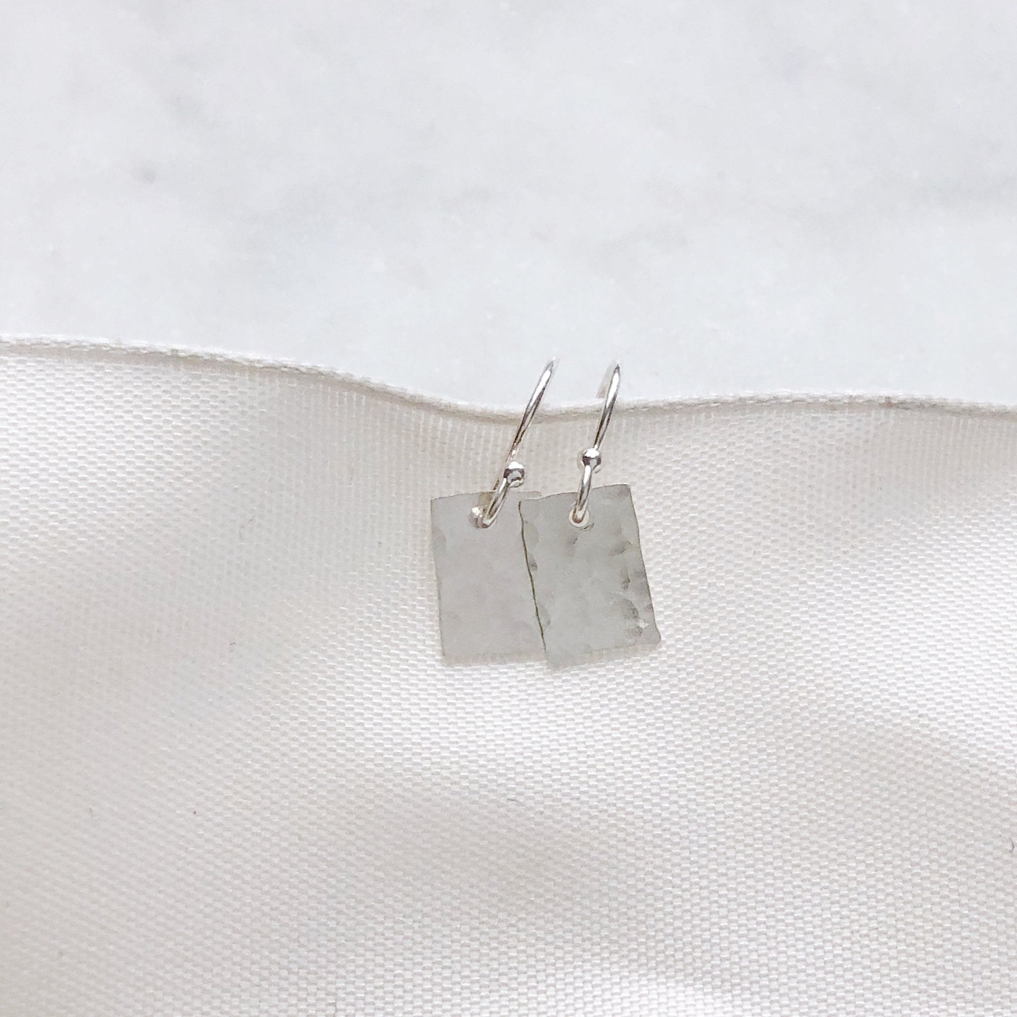 Silver Lordes Earrings by Sarah Cornwell Jewelry. Dainty, shimmery, silver textured rectangle earrings on a white background.