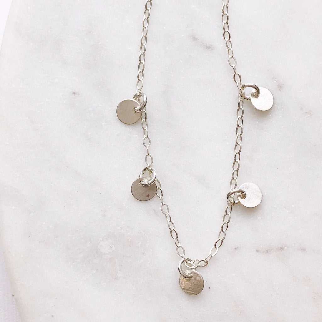 Silver necklace with 5 tiny silver discs. Mae Necklace by Sarah Cornwell Jewelry
