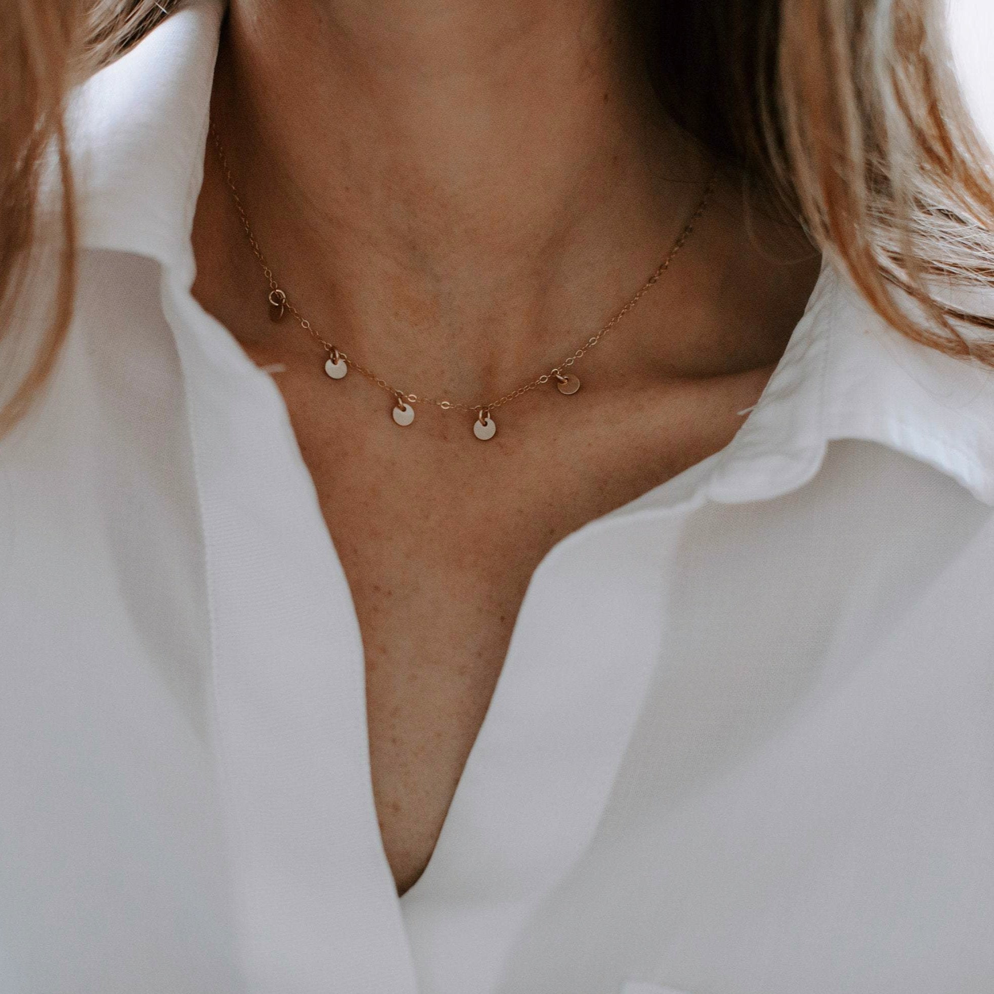 Woman's neckline wearing white button down with gold necklace with 5 tiny gold discs. Mae Necklace by Sarah Cornwell Jewelry