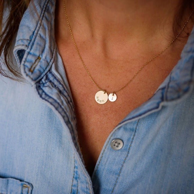 Woman's neck wearing denim button down with gold mama stamped disc necklace with a tiny stamped initial disc. Mama Necklace by Sarah Cornwell Jewelry
