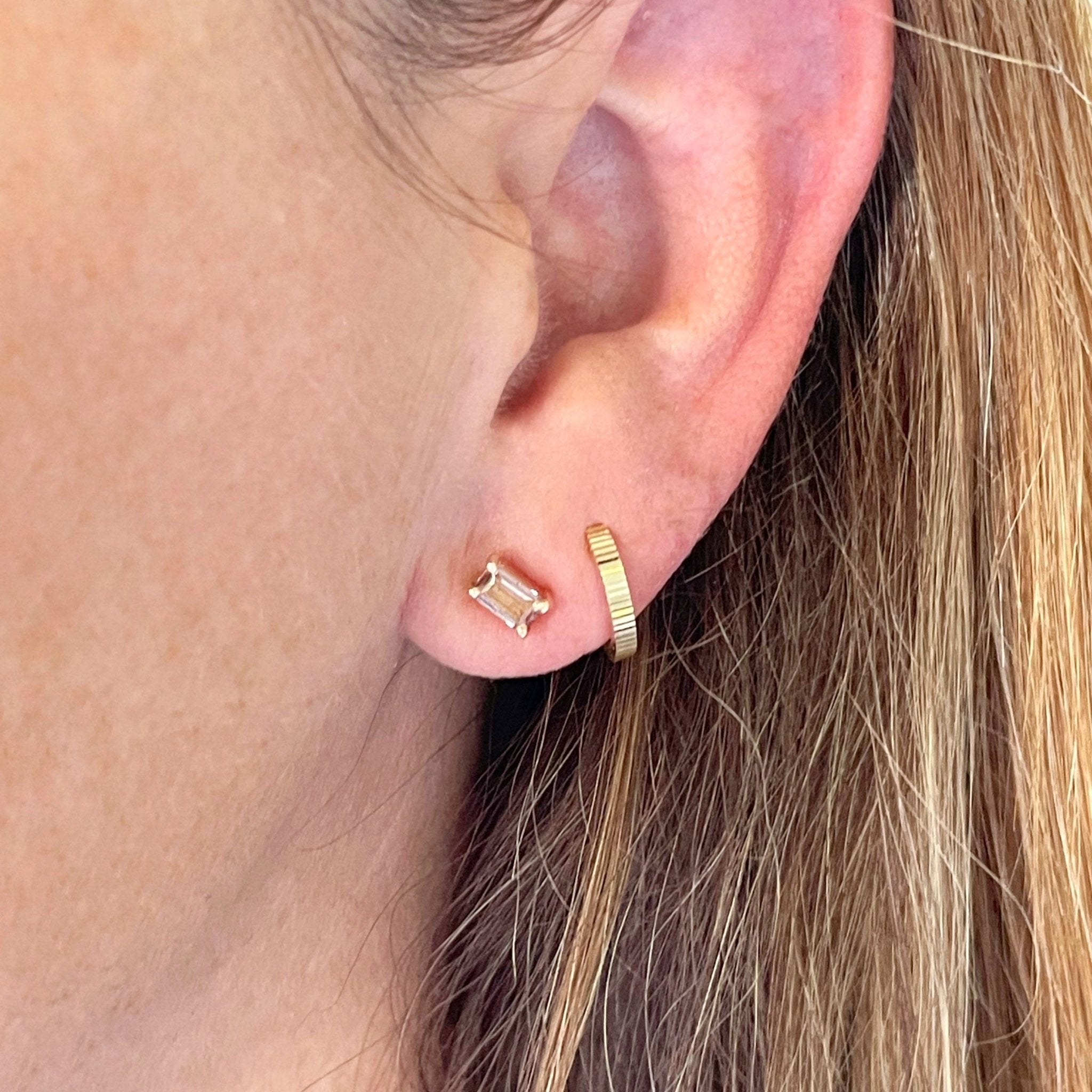 Close up of woman's ear wearing 14K gold and 1 carat rectangular cut peach pink tourmaline stud earring with gold huggie earring. Michelle Studs by Sarah Cornwell Jewelry