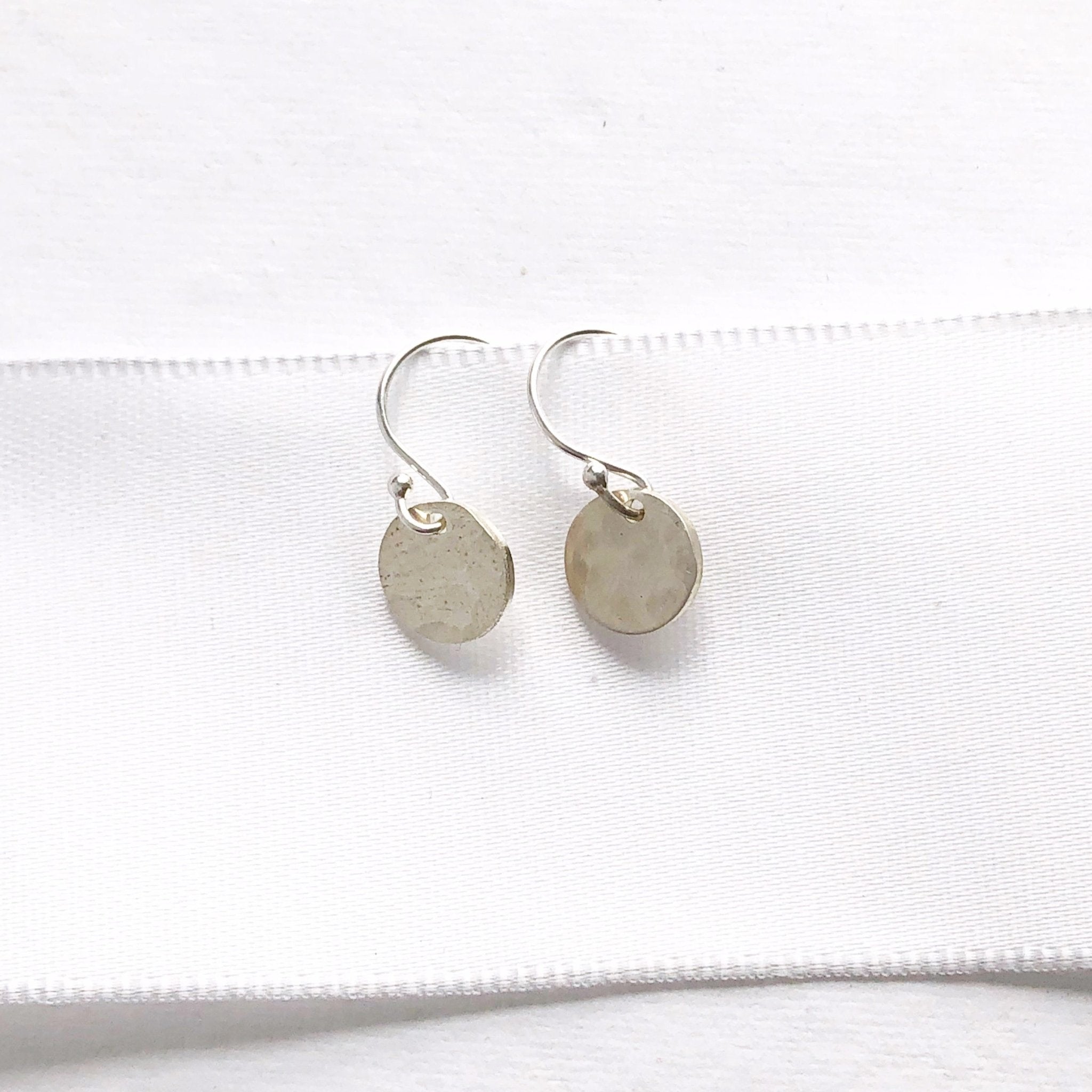 Silver Monica Earrings by Sarah Cornwell Jewelry. Shimmery, dainty silver 3/8 inch textured disc earrings on a white background.