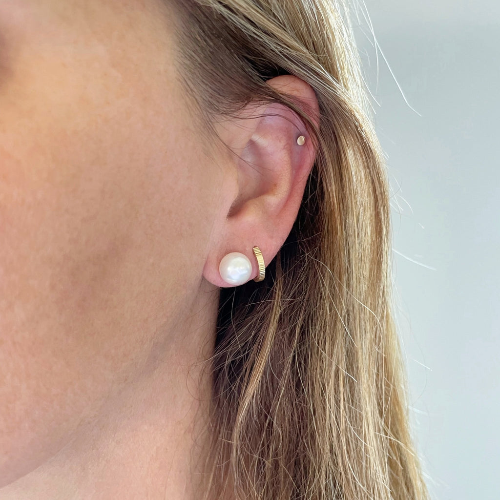 Close up of woman with blonde hair wearing oversized 9.5-10 mm creamy white oyster pearl stud earrings. Oyster Pearl Studs by Sarah Cornwell Jewelry