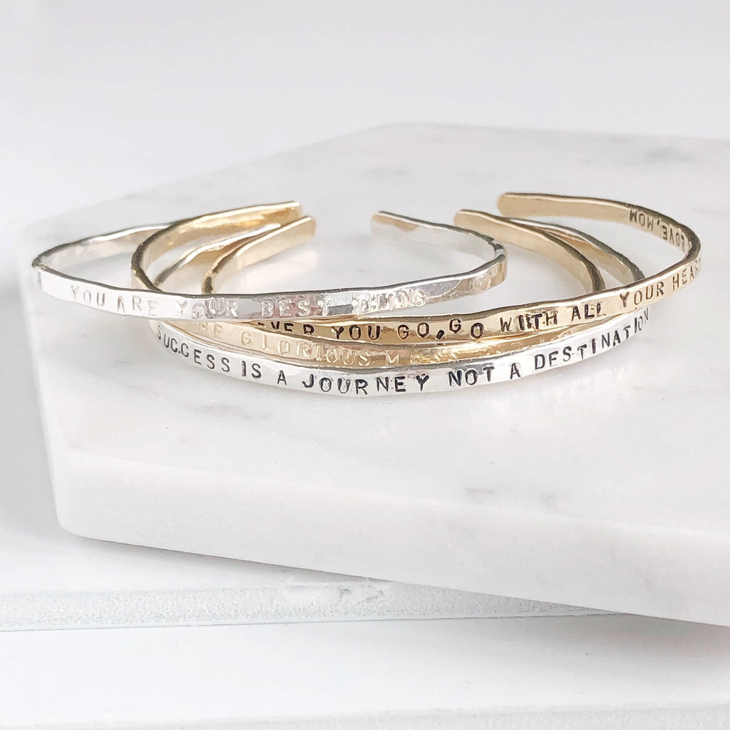 4 gold and silver textured bangle bracelets with stamped personalization on the outside. Personalized Caroline Bangle by Sarah Cornwell Jewelry