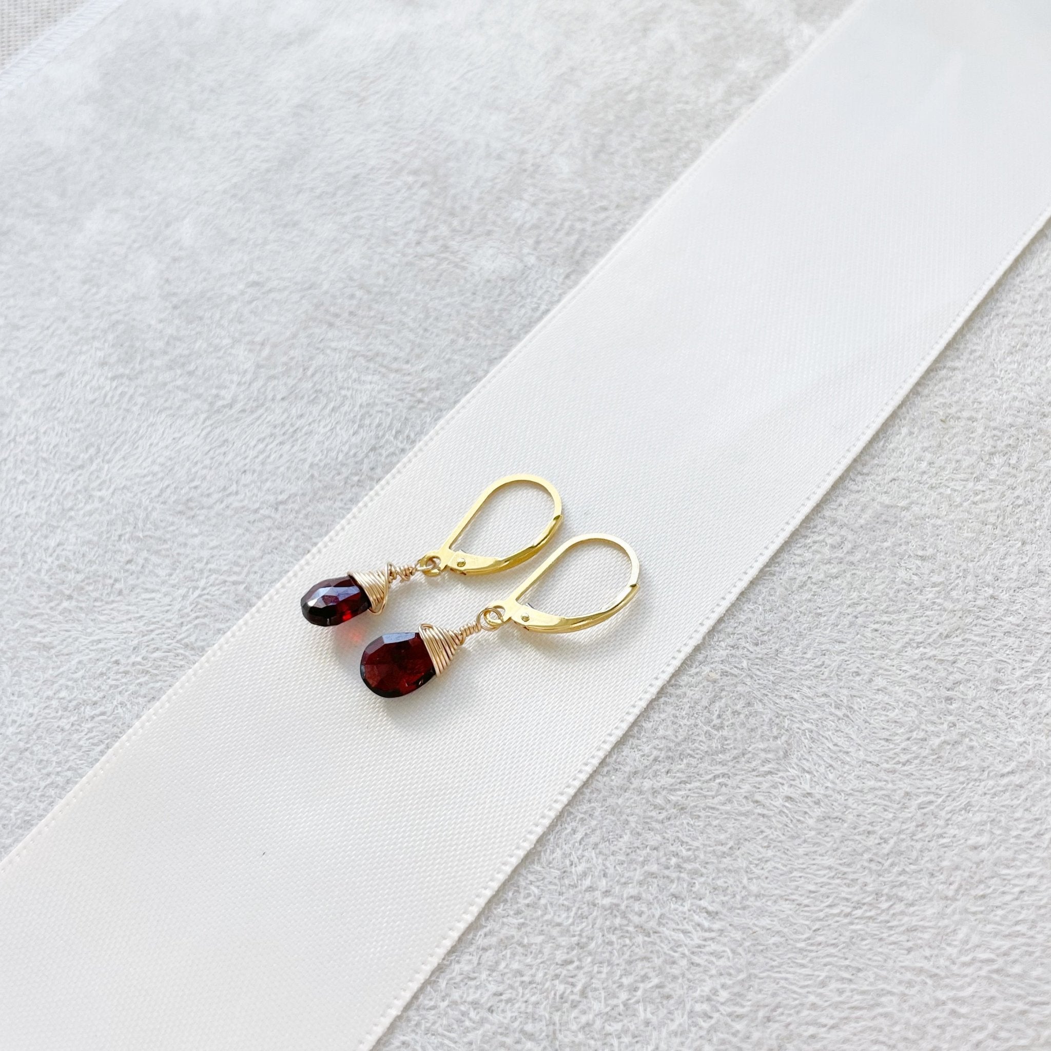 Gold wire wrapped garnet gemstone drop earrings with a lever back. Poppy Garnet Earrings by Sarah Cornwell Jewelry