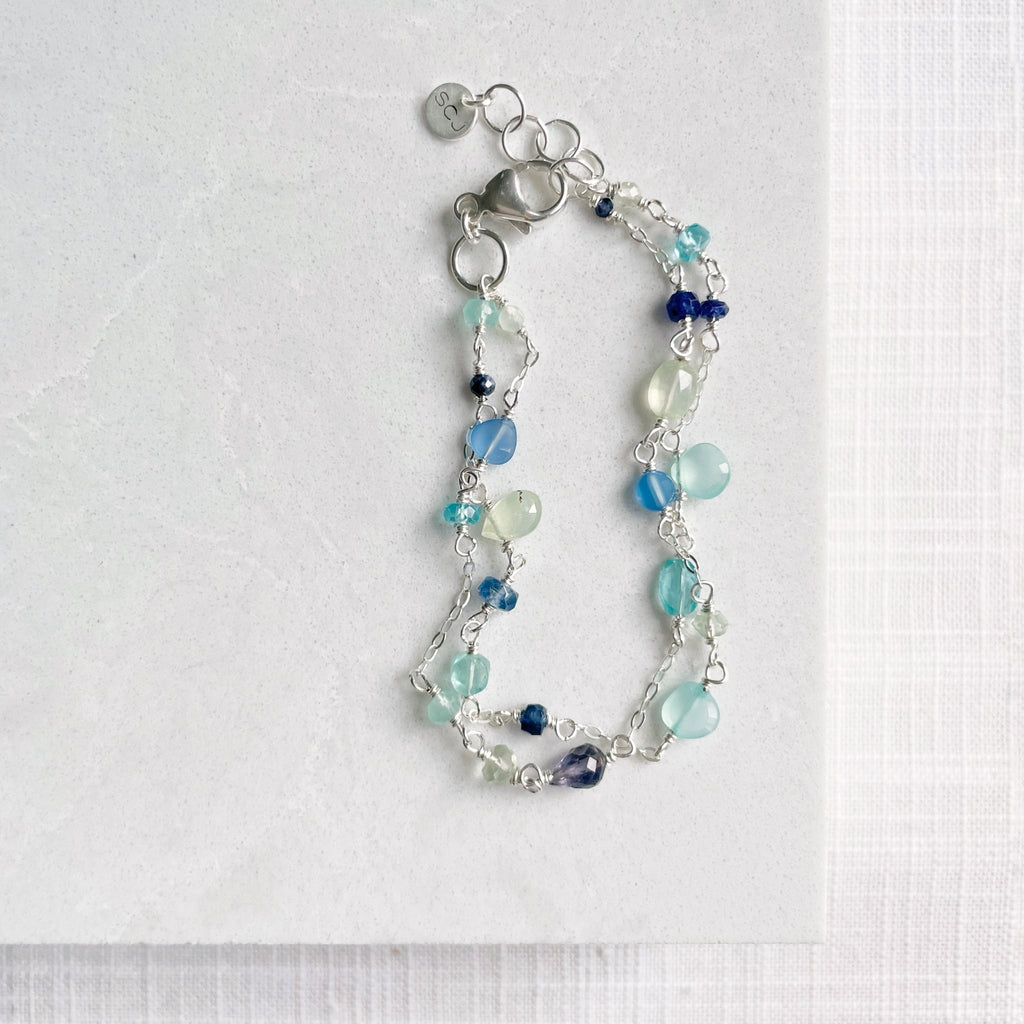 Silver double strand blue hued gemstone bracelet with hand wire wrapped prehnite, blue sapphire, chalcedony, and apatite gemstones. Poppy Seaside Bracelet by Sarah Cornwell Jewelry