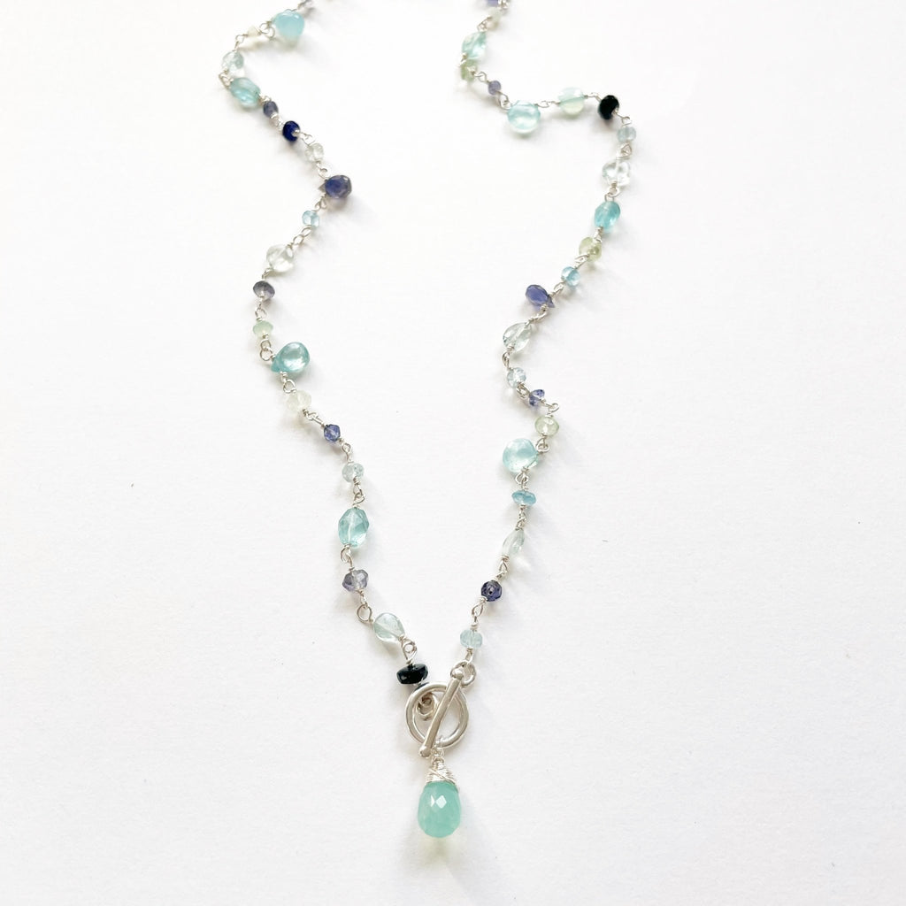 Silver gemstone necklaces with wire wrapped blue chalcedony, aqua chalcedony, prehnite, iolite, blue sapphires, and aquamarine gemstones with a front toggle closure and large chalcedony drop. Poppy Seaside Front Toggle by Sarah Cornwell Jewelry
