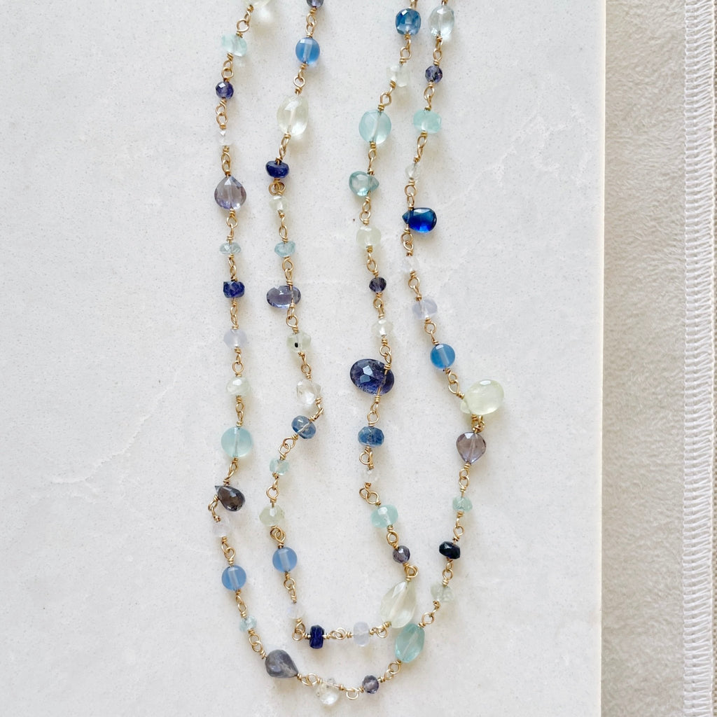 Gold and gemstone long statement necklace with wire wrapped blue chalcedony, aqua chalcedony, prehnite, iolite, blue sapphires, and aquamarine gemstones. Poppy Seaside Necklace by Sarah Cornwell Jewelry