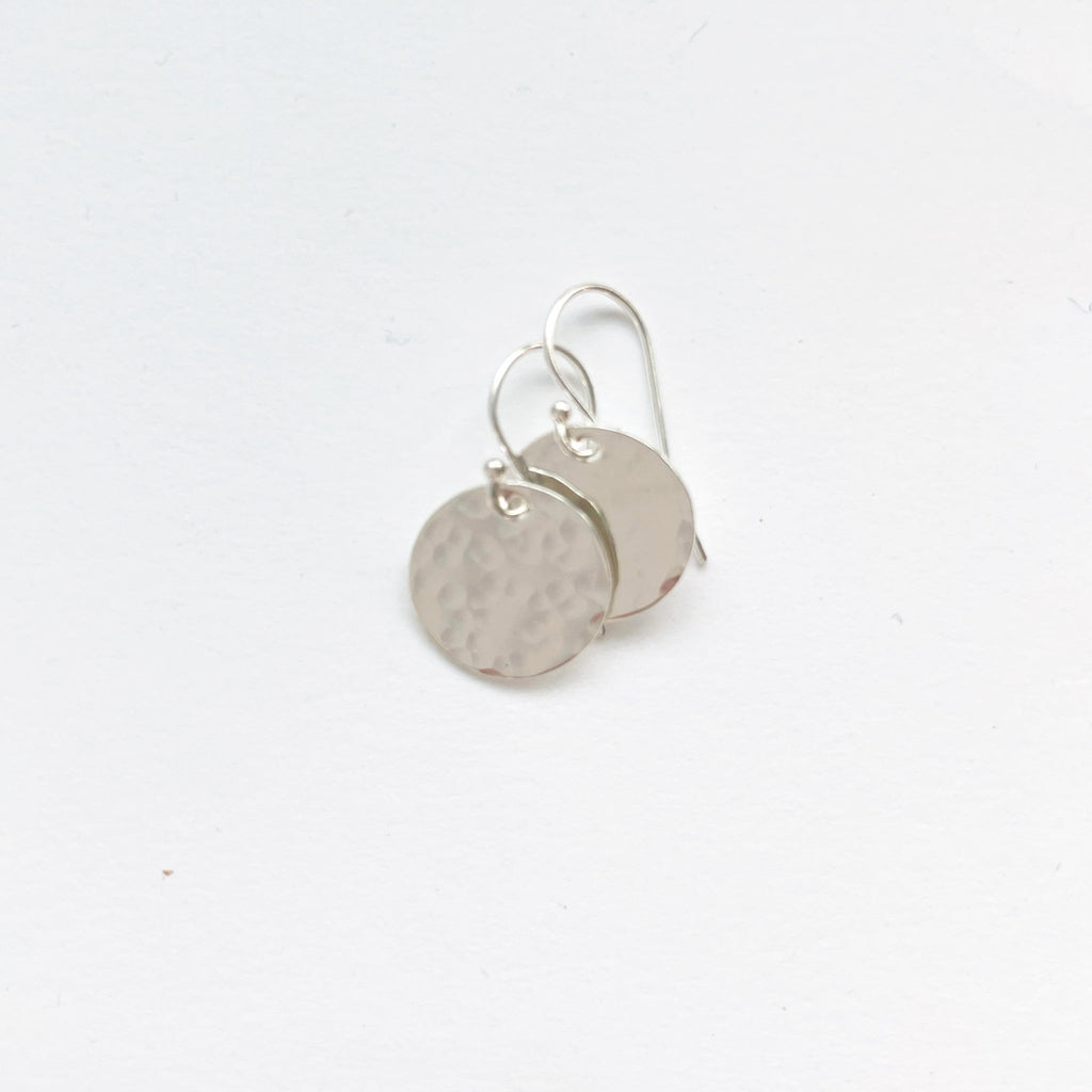 Silver Rachel Earrings by Sarah Cornwell Jewelry. Shimmery, dainty silver 1/2 inch textured disc earrings on a white background.
