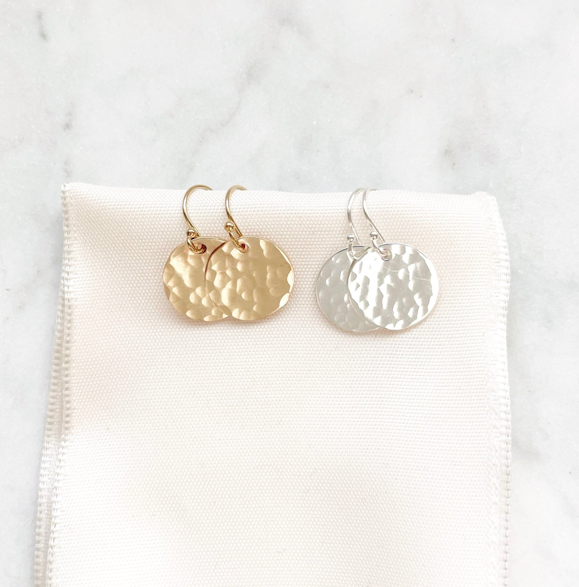 Rachel Earrings by Sarah Cornwell Jewelry. 2 pairs of shimmery, dainty gold and silver 1/2 inch textured disc earrings on a cream background.