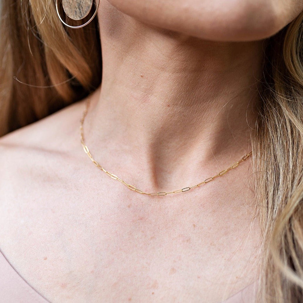 Woman's neckline with gold rectangle link paperclip chain necklace and textured disc earrings. Savannah Chain by Sarah Cornwell Jewelry