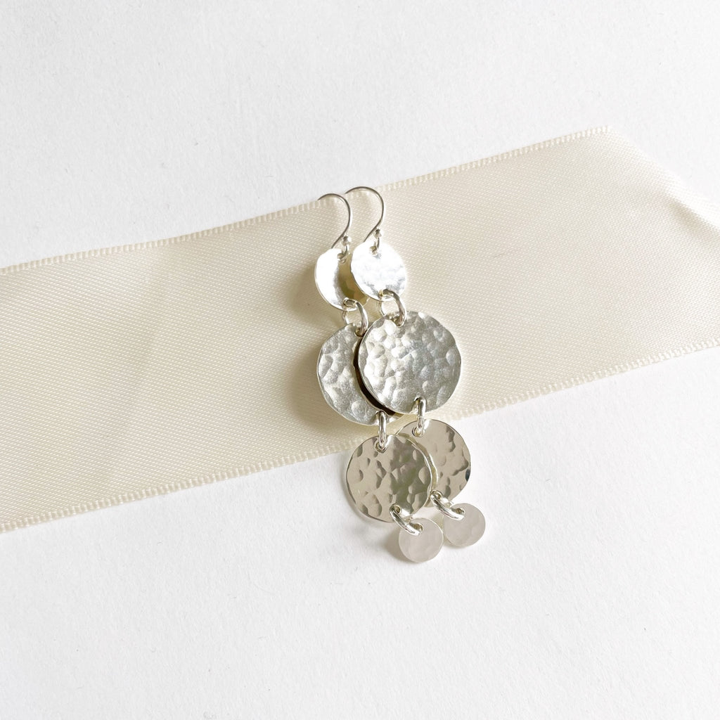 Silver South Beach Earrings by Sarah Cornwell Jewelry. Silver statement earrings with 4 textured gold discs of various sizes with a 2.25 inch drop on a white background.