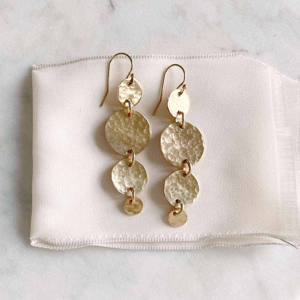 Gold South Beach Earrings  by Sarah Cornwell Jewelry. Gold statement earrings with 4 textured gold discs of various sizes with a 2.25 inch drop on a white background.